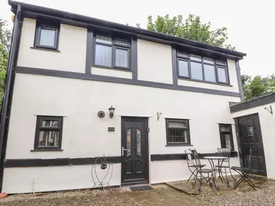 a white house with black windows and a table at Mayfield Cottage in Blackpool