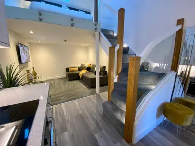 a living room with a staircase in a house at King Street Serviced Apartments in Lancaster