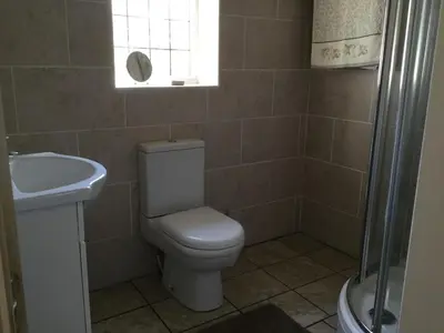 a bathroom with a toilet and a sink and a window at Grooms cottage in Thornton