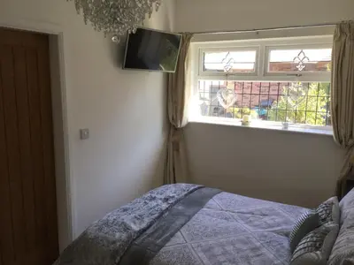 a bedroom with a bed and a window and a tv at Grooms cottage in Thornton