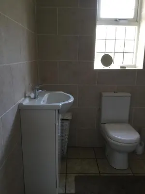 a bathroom with a toilet and a sink and a window at Grooms cottage in Thornton