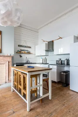 a kitchen with white cabinets and a wooden table at Beach Lookout - SEA VIEWS in Lytham St Annes