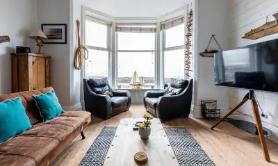 a living room with a couch and chairs and a tv at Beach Lookout - SEA VIEWS in Lytham St Annes