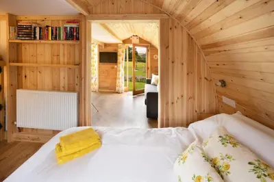 a bedroom with a white bed in a wooden room at Orchard Glamping in Catterall