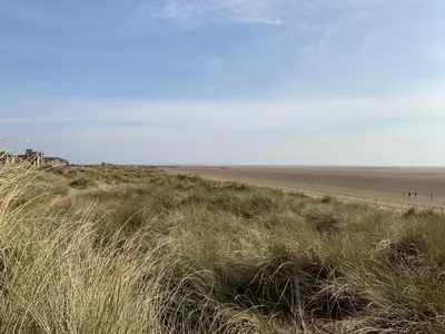 a beach with a fence and a field of grass at Beach Cottage in Lytham St Annes