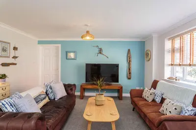a living room with brown leather couches and a table at Beach Cottage in Lytham St Annes