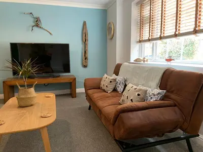 a living room with a brown couch and a tv at Beach Cottage in Lytham St Annes