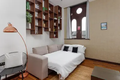 a room with a bed and a couch and a window at FLATZY - Victoria Street Apartment - Heart of City Centre in Liverpool