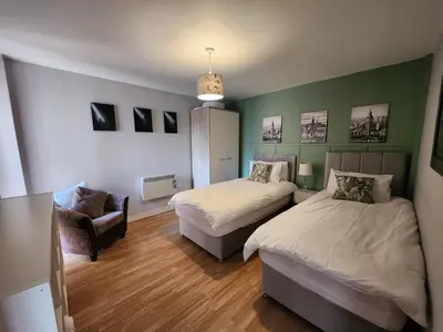 a bedroom with two beds and a chair in it at Modern central Penthouse - 1 FreeParking in Liverpool