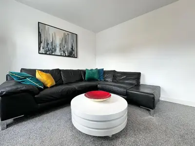 a living room with a black leather couch and a white table at The Birketts Inn, 4 - Bed, Sleeps 8, Pets Welcome in Ulverston