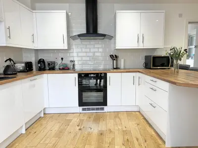 a white kitchen with white cabinets and a wooden floor at The Birketts Inn, 4 - Bed, Sleeps 8, Pets Welcome in Ulverston
