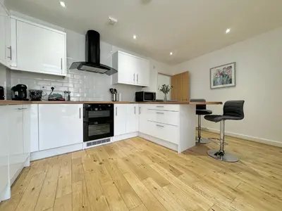 a kitchen with white cabinets and a wooden floor at The Birketts Inn, 4 - Bed, Sleeps 8, Pets Welcome in Ulverston