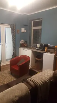 a living room with a red chair and a kitchen at Atlantic cottage in Blackpool