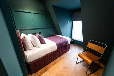 a small bedroom with a bed and a chair at Duke Street Boutique Hotel in Liverpool