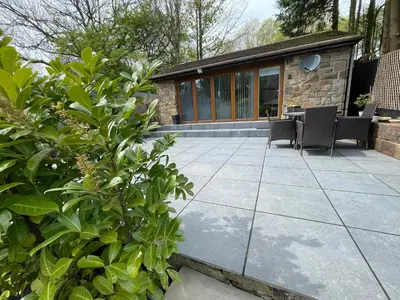 a patio with chairs and a table and a building at Dean Clough Lodge - Contemporary self contained studio in Wilpshire