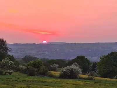 a sunset over a field with the sun in the horizon at Dean Clough Lodge - Contemporary self contained studio in Wilpshire