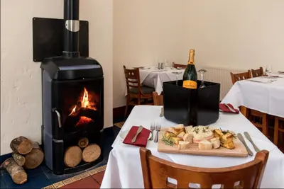 a table with a fireplace and a plate of food at 12 Borwick Lakes- Newly Refurbished in Carnforth
