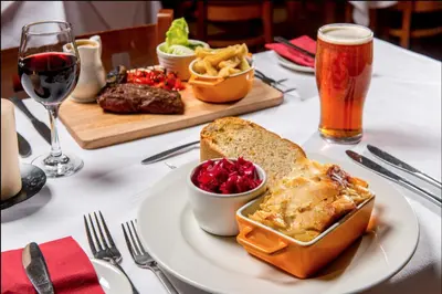 a table with a plate of food and a glass of beer at 12 Borwick Lakes- Newly Refurbished in Carnforth