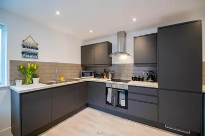 a kitchen with black cabinets and a sink at Charles Alexander Short Stay - Windmill House Apartments in Lytham St Annes