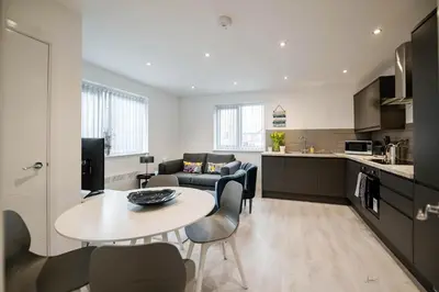 a kitchen and a living room with a table and chairs at Charles Alexander Short Stay - Windmill House Apartments in Lytham St Annes