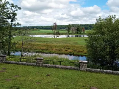 a fence in a field with a river at FSC Castle Head Hostel in Grange Over Sands