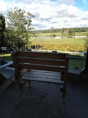 a wooden bench with a view of a lake at FSC Castle Head Hostel in Grange Over Sands