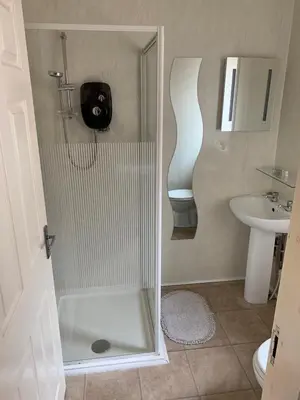 a bathroom with a shower with a toilet and a sink at Alandene in Blackpool