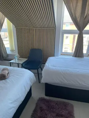 a bedroom with two beds and a chair and a window at Mr sandman’s hotel in Blackpool
