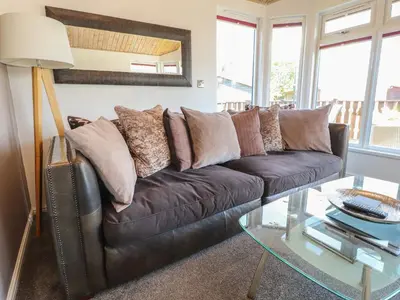 a living room with a leather couch and a glass table at Doormouse Lodge in Carnforth