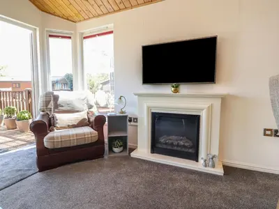 a living room with a fireplace and a flat screen tv at Doormouse Lodge in Carnforth