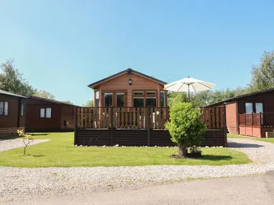 a cabin with an umbrella in front of it at Doormouse Lodge in Carnforth