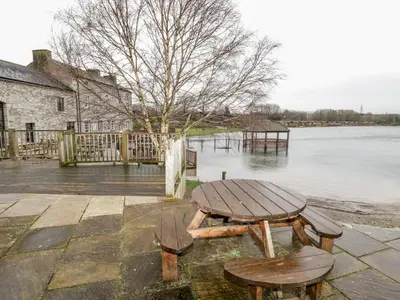 a picnic table and two chairs next to a body of water at Doormouse Lodge in Carnforth