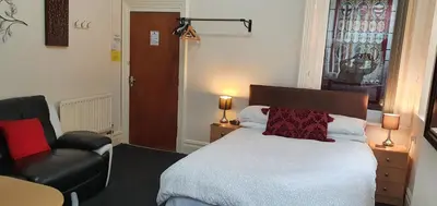 a bedroom with a bed and a chair and a window at Norwyn Court Holiday Apartments in Blackpool