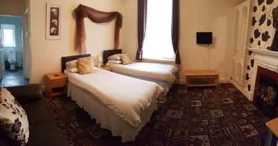 a hotel room with two beds and a window at Norwyn Court Holiday Apartments in Blackpool