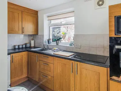 a kitchen with wooden cabinets and a sink and a window at Sunnyside Cottage in Crossens