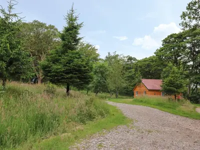 a dirt road leading to a red barn and trees at Park Brook Dell in Preston