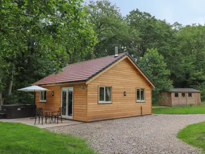 a small wooden cabin with a table and an umbrella at Park Brook Dell in Preston