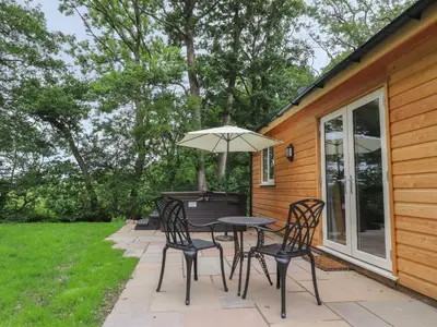 a patio with a table and chairs and an umbrella at Park Brook Dell in Preston