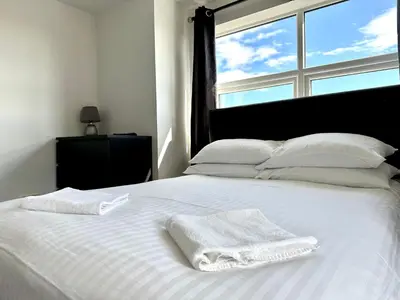 a white bed with two towels on it with a window at Sienna Family Holiday Apartments by Blackpool Service Apartments in Blackpool
