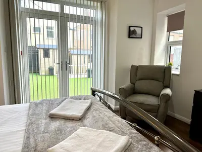 a bedroom with a bed and a chair and a window at Sienna Family Holiday Apartments by Blackpool Service Apartments in Blackpool