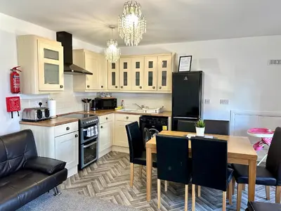 a kitchen with a table and a black refrigerator at Sienna Family Holiday Apartments by Blackpool Service Apartments in Blackpool