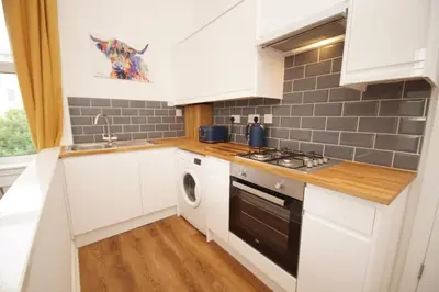 a kitchen with white cabinets and a sink and a stove at Grosvenor Lodge Birkdale Southport in Southport