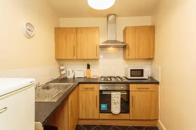a kitchen with wooden cabinets and a stove top oven at Cherry Property - Pear Suite in Blackpool