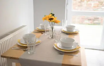 a table with plates and glasses and a vase of flowers at Buchanan House Sasco Apartments in Blackpool