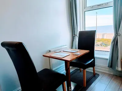 a table and two chairs in a room with a window at Seahawk Holiday Apartments in Cleveleys
