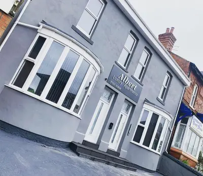 a white house with a sign on the front of it at Albert Hottub & Jacuzzi Apartments in Blackpool