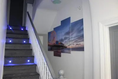 a staircase with a painting on the wall and blue lights at Albert Hottub & Jacuzzi Apartments in Blackpool