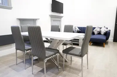 a dining room with a table and chairs and a couch at 16 Queen Avenue Collection by Happy Days in Liverpool