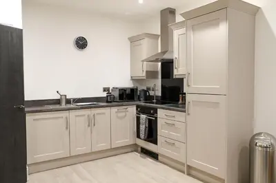 a kitchen with white cabinets and a sink at 16 Queen Avenue Collection by Happy Days in Liverpool