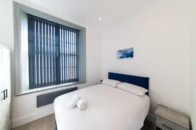 a bedroom with a white bed and a window at 16 Queen Avenue Collection by Happy Days in Liverpool